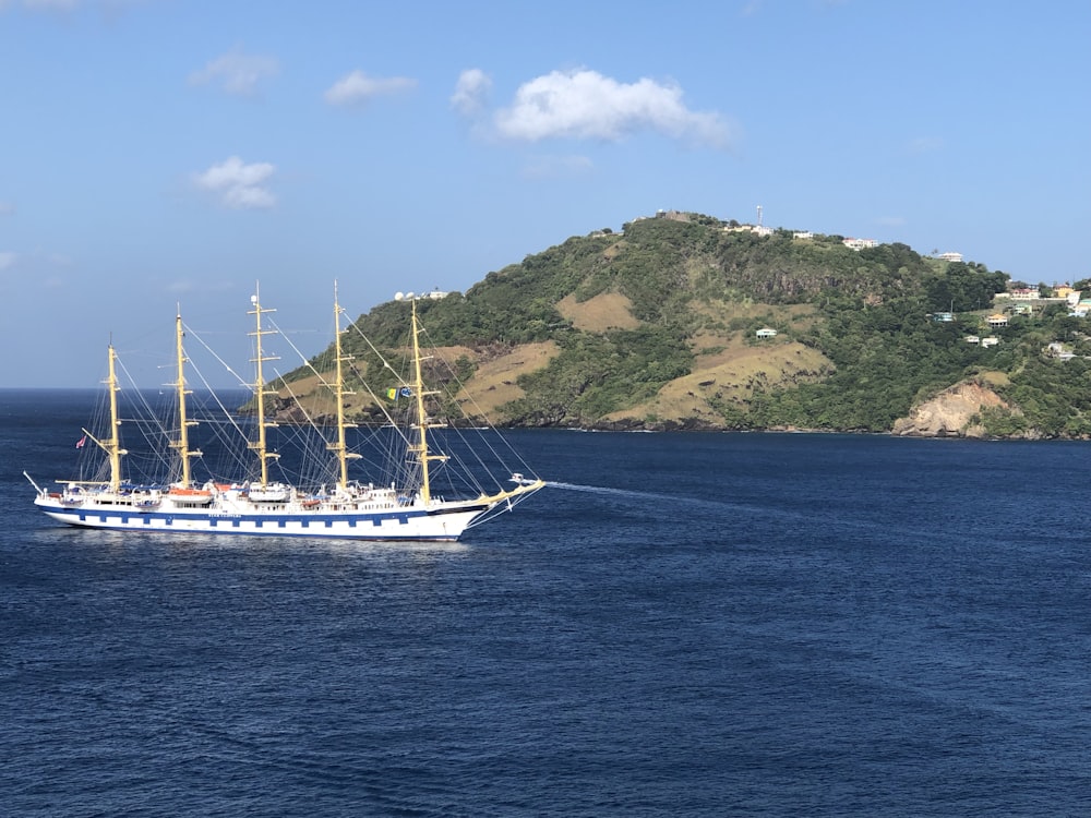 white boat on sea near green mountain under blue sky during daytime