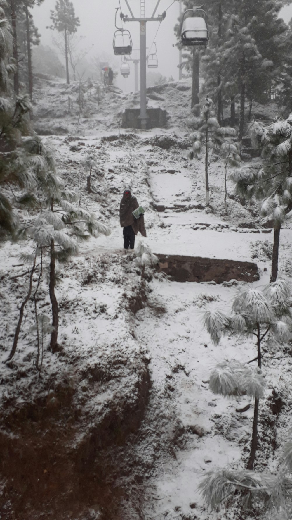 person in black jacket walking on snow covered ground during daytime