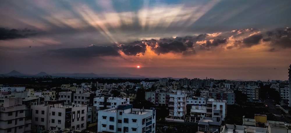 city with high rise buildings under orange and gray cloudy sky during sunset