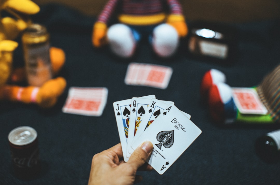 person holding playing cards near red and white ball