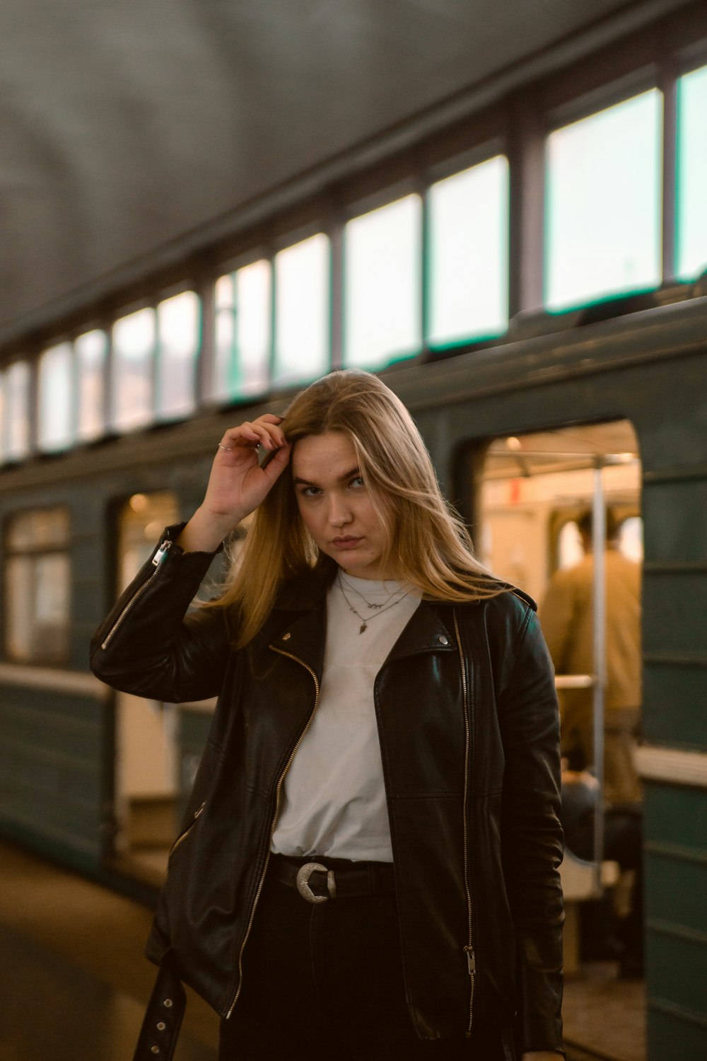 woman in black leather jacket standing near glass window