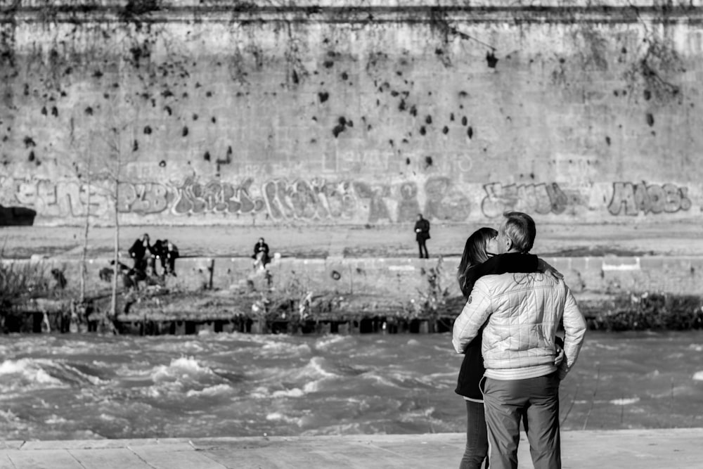 grayscale photo of man and woman walking on beach