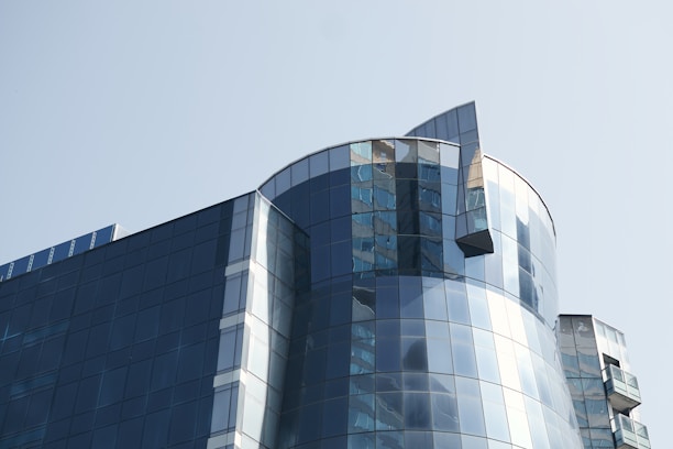 A modern glass building reflecting the Dallas skyline under a clear blue sky.