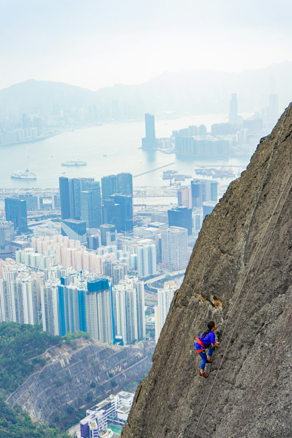 man in red shirt and blue pants sitting on brown rock during daytime