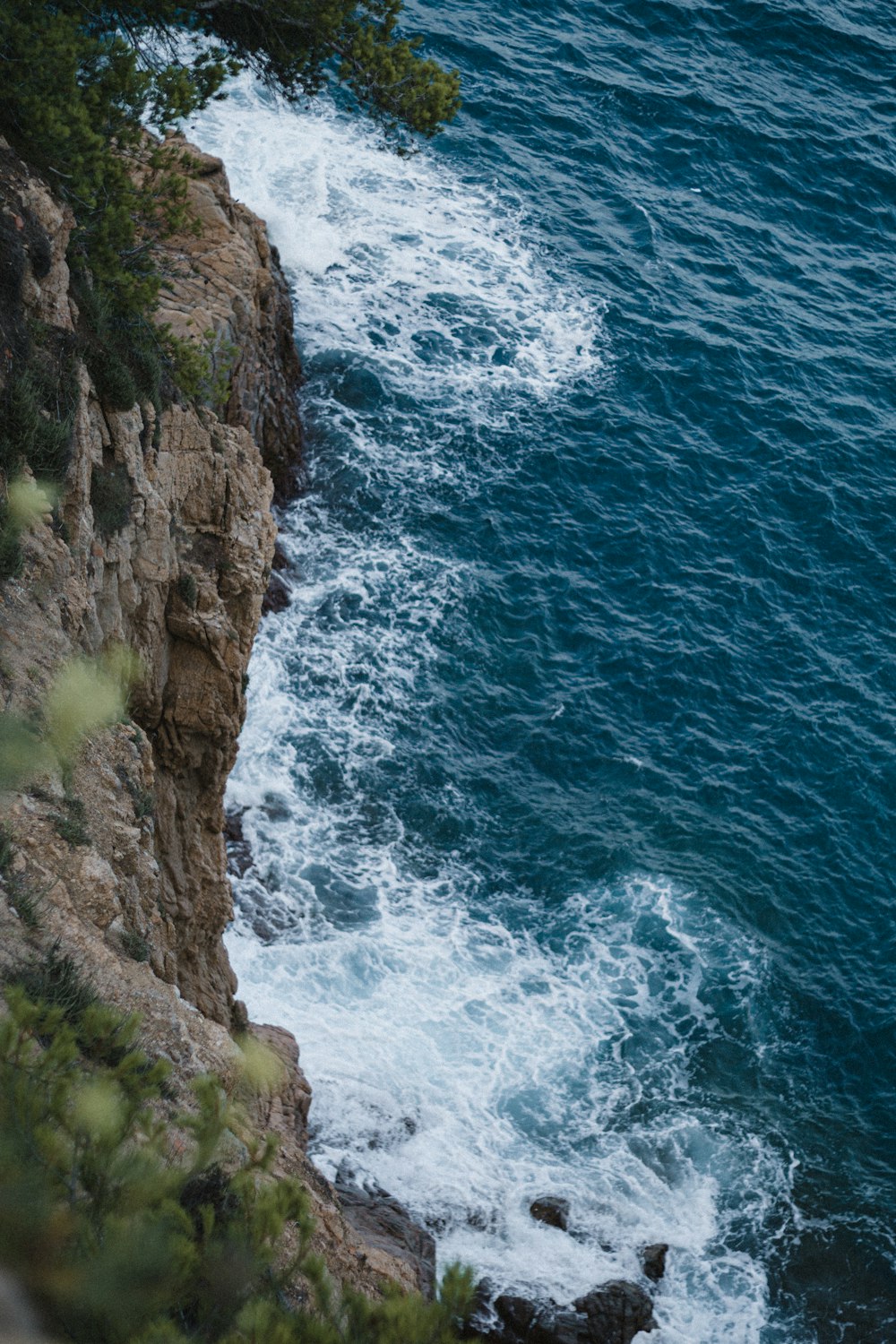 Montaña rocosa marrón junto al mar azul durante el día