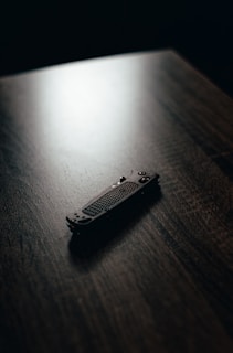 A close-up of a well-used, classic camping knife resting on a wooden table with morning light casting soft shadows.