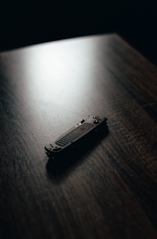 A close-up of a well-used, classic camping knife resting on a wooden table with morning light casting soft shadows.