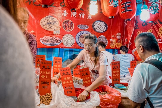 woman in white crew neck t-shirt holding white plastic bag in Chinatown Singapore