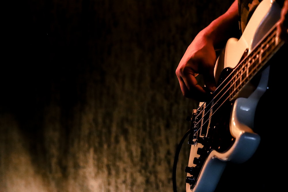 person playing white and black electric guitar