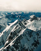 Snow-covered peaks piercing through soft, rolling clouds.