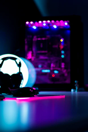Close-up of sleek gaming peripherals glowing with ice blue LED lights on a black desk setup.