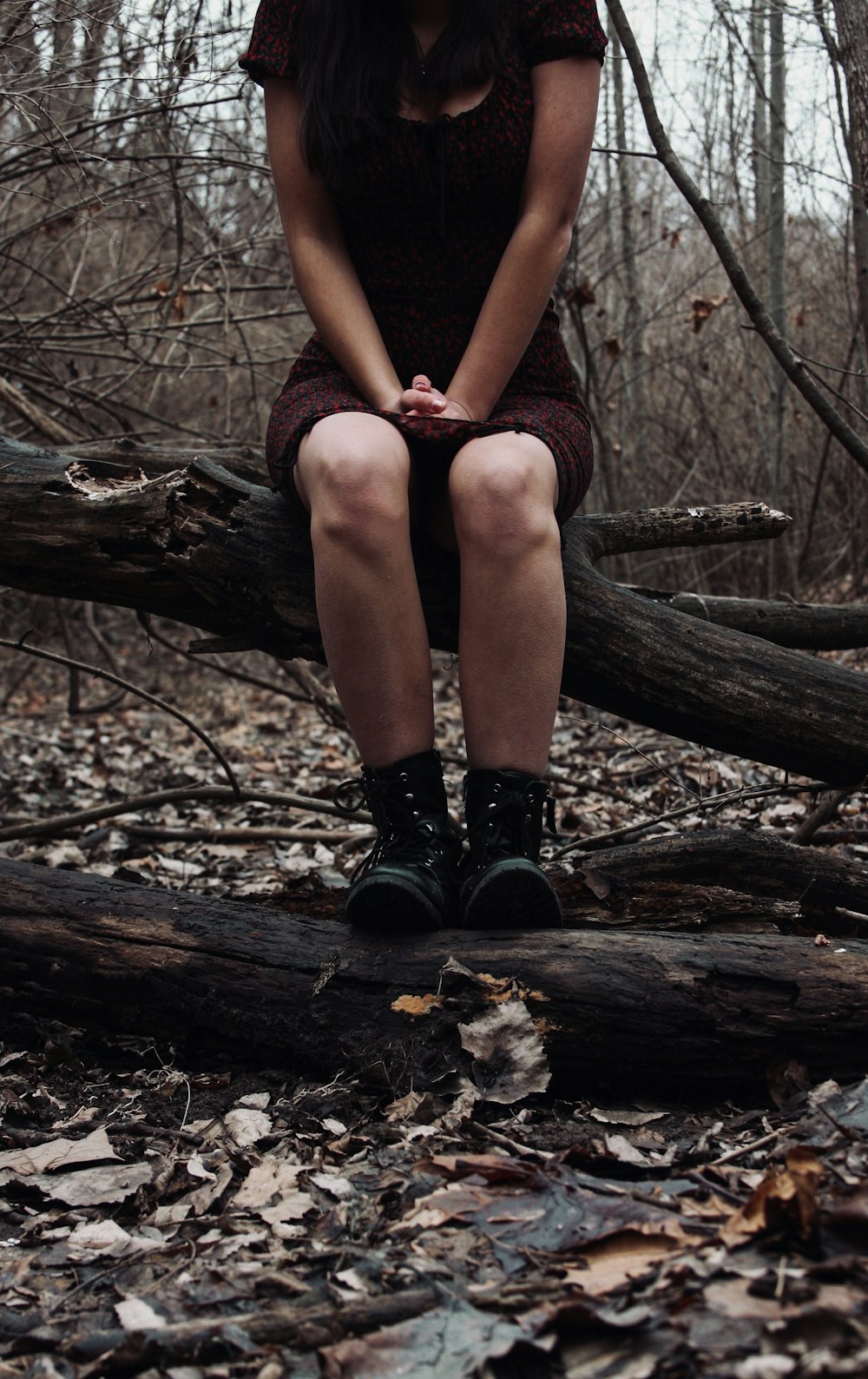 Frau in schwarzen Strümpfen sitzt auf braunem Baumstamm