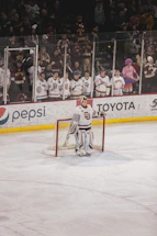 A friendly customer service representative with hockey gear in the background ready to assist.
