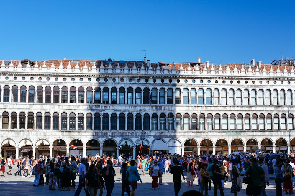 people standing in front of white concrete building during daytime