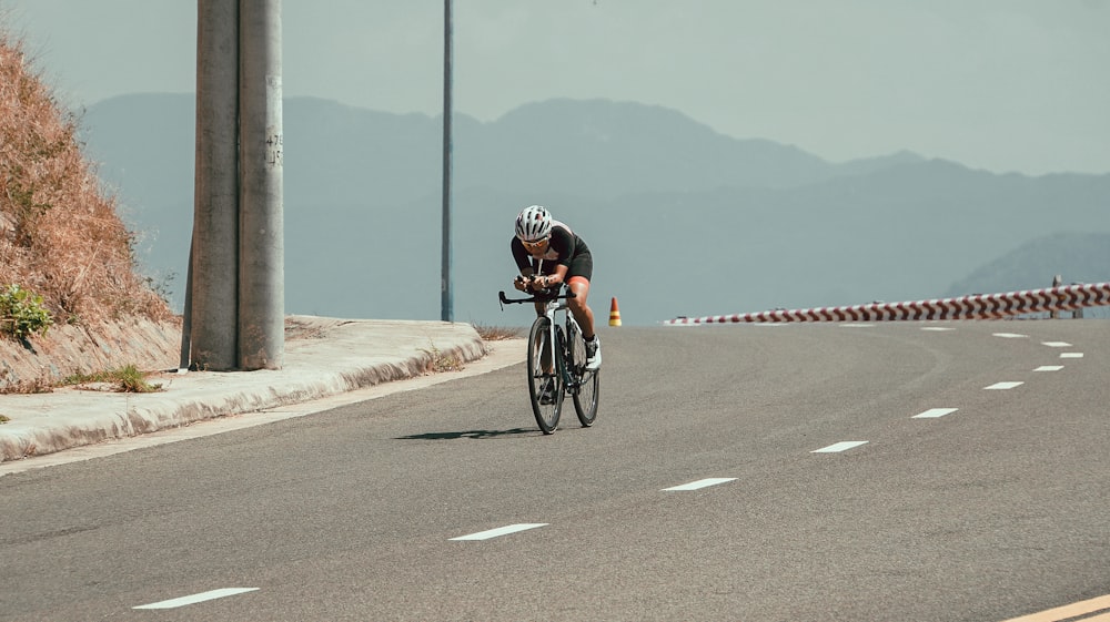 man in black and red helmet riding bicycle on road during daytime