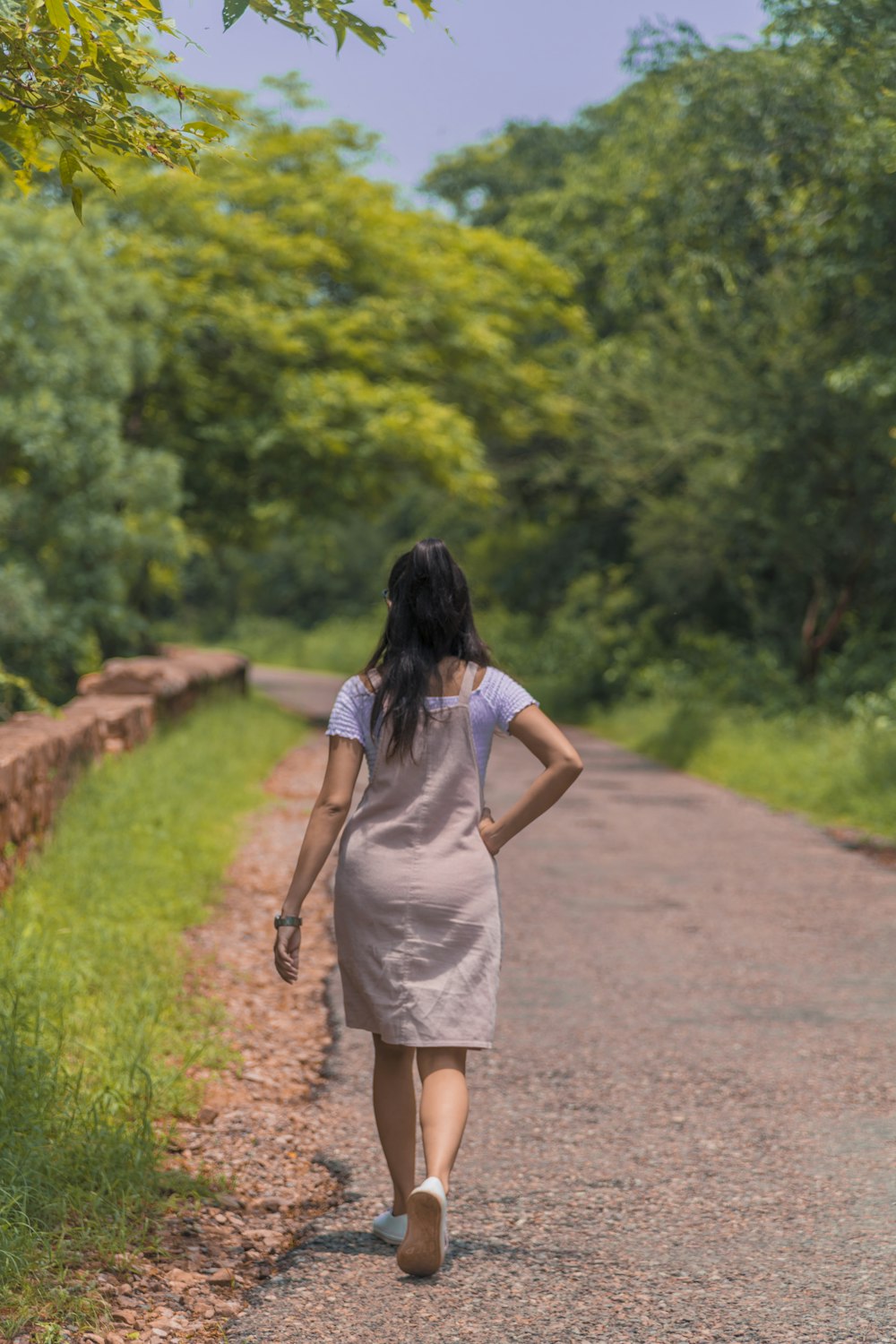 woman in white dress walking on pathway during daytime