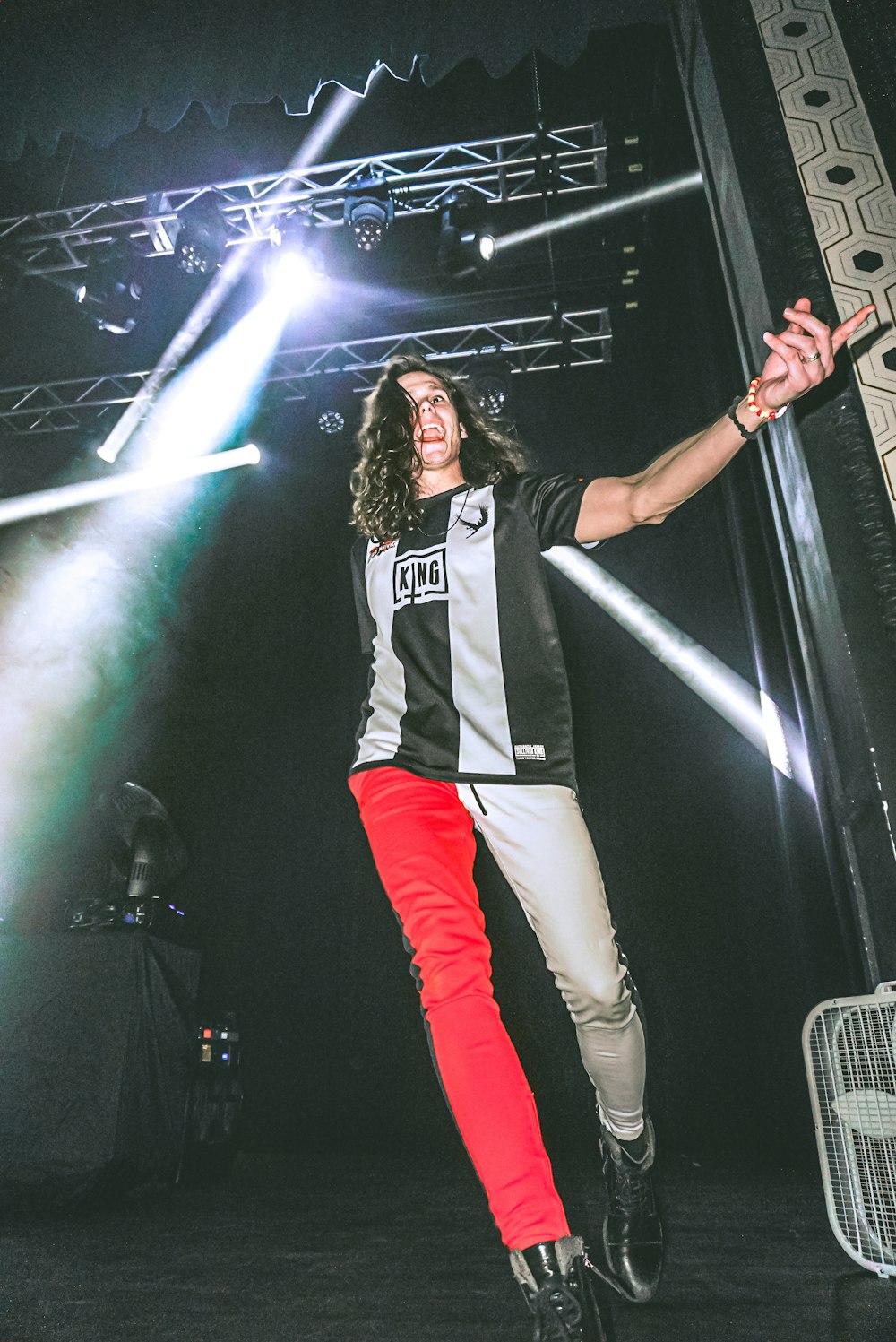 woman in white and black shirt and red pants standing on stage