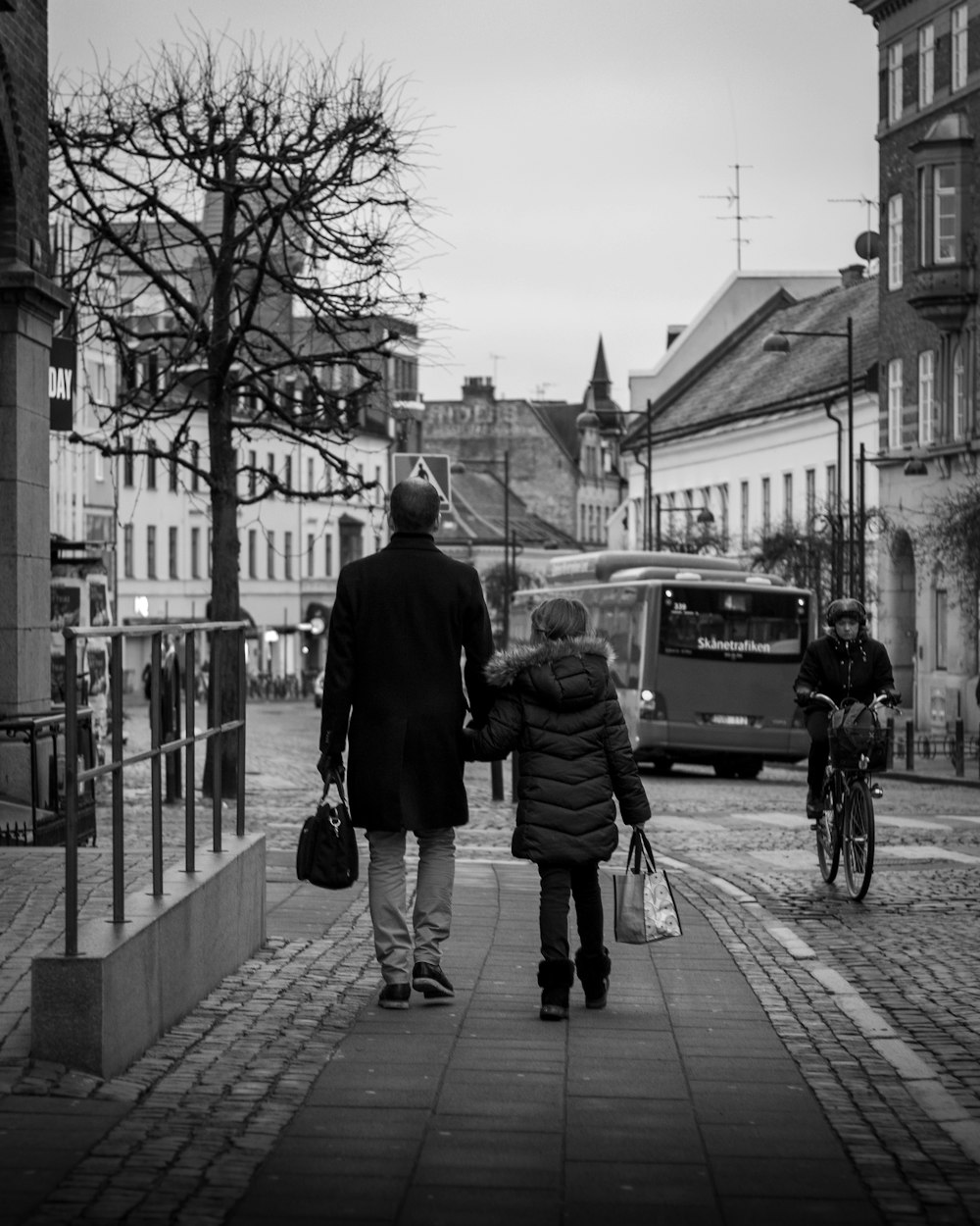 grayscale photo of man and woman walking on sidewalk