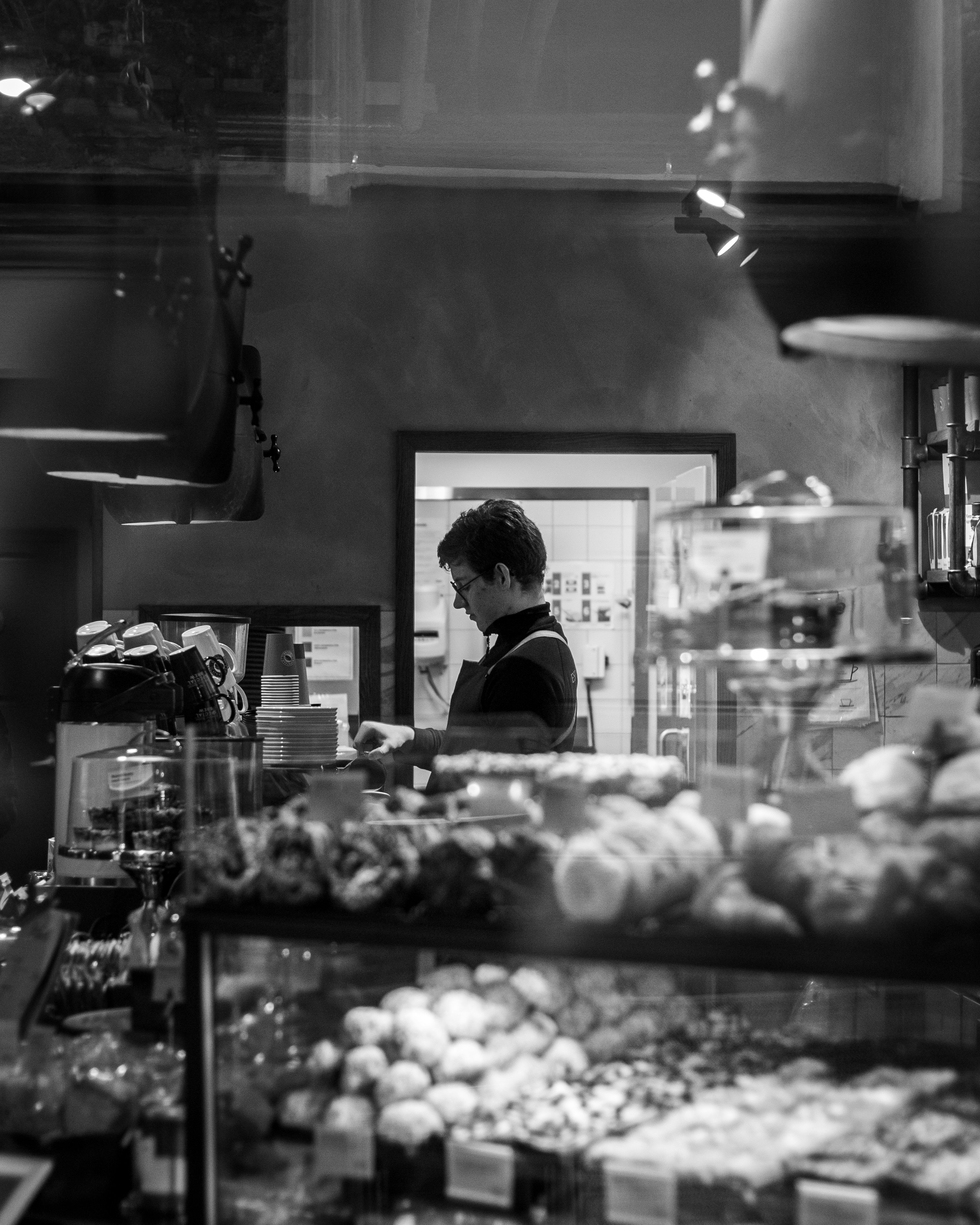 grayscale photo of man in black shirt standing in front of mirror