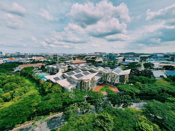 A modern sustainable residential building complex with solar panels and green roofs under clear sky.