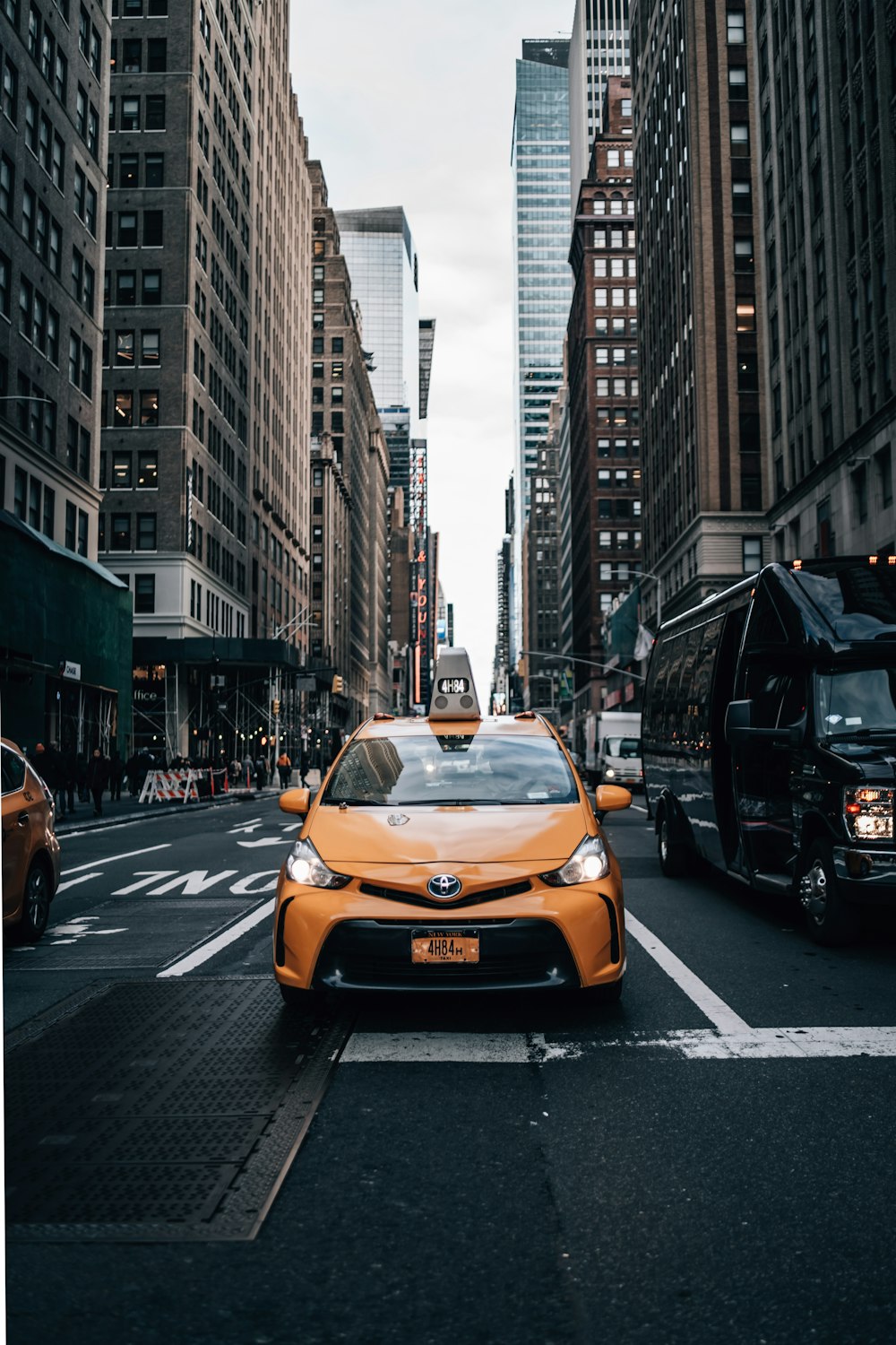 yellow car on the road in between of buildings during daytime