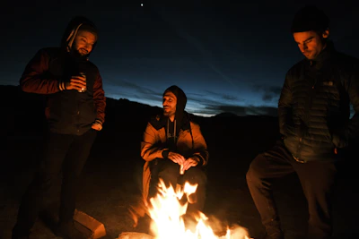 Evening scene with riders gathered around a small fire near their gear on the mountain.