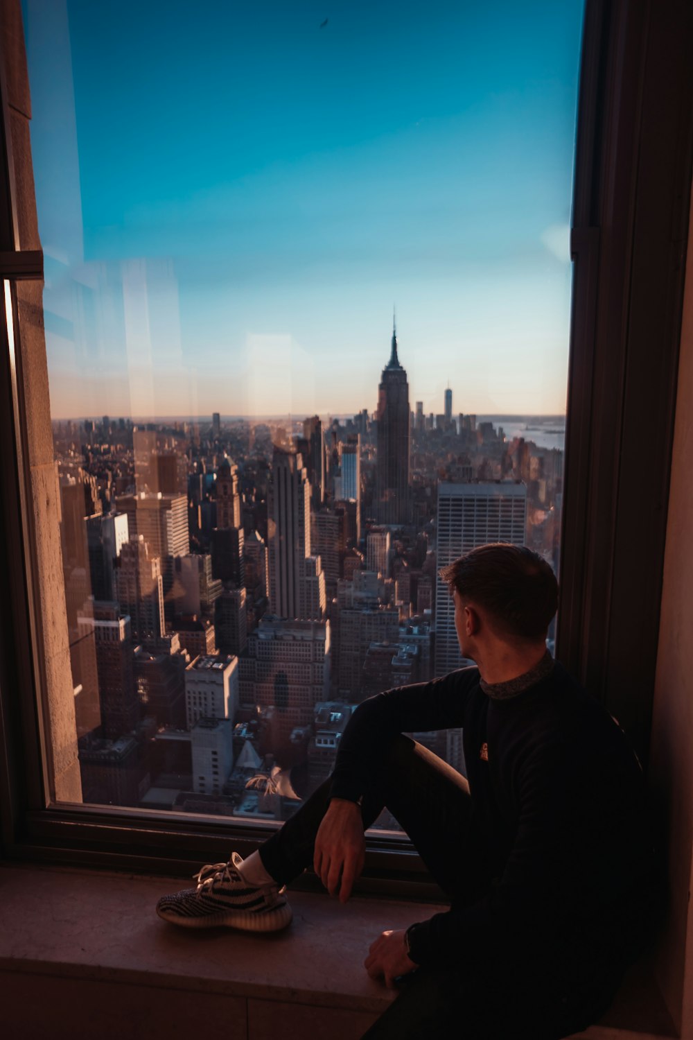 man in black crew neck t-shirt standing near window during daytime