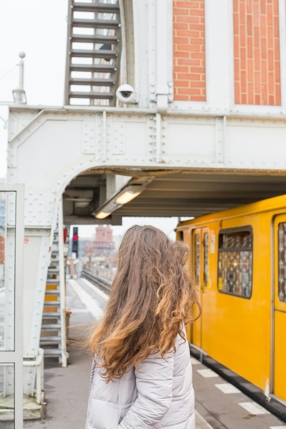woman in white shirt standing near yellow train during daytime