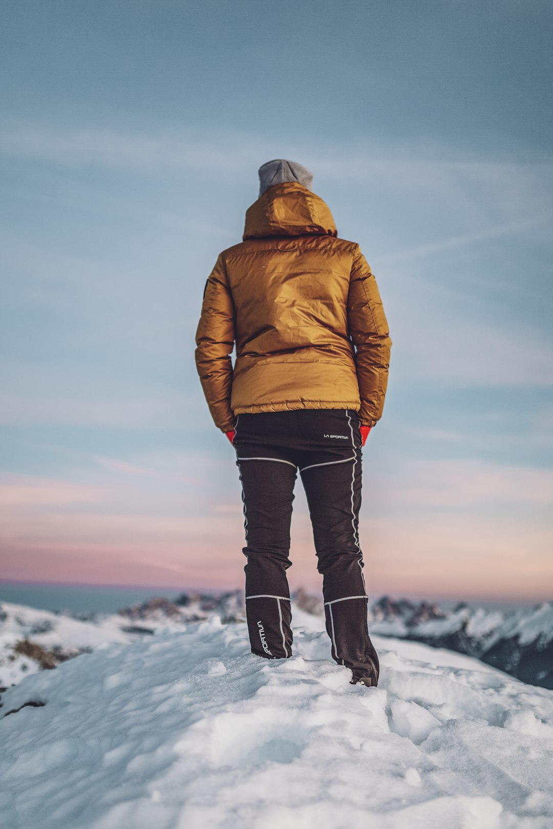 person in brown jacket standing on snow covered ground during daytime