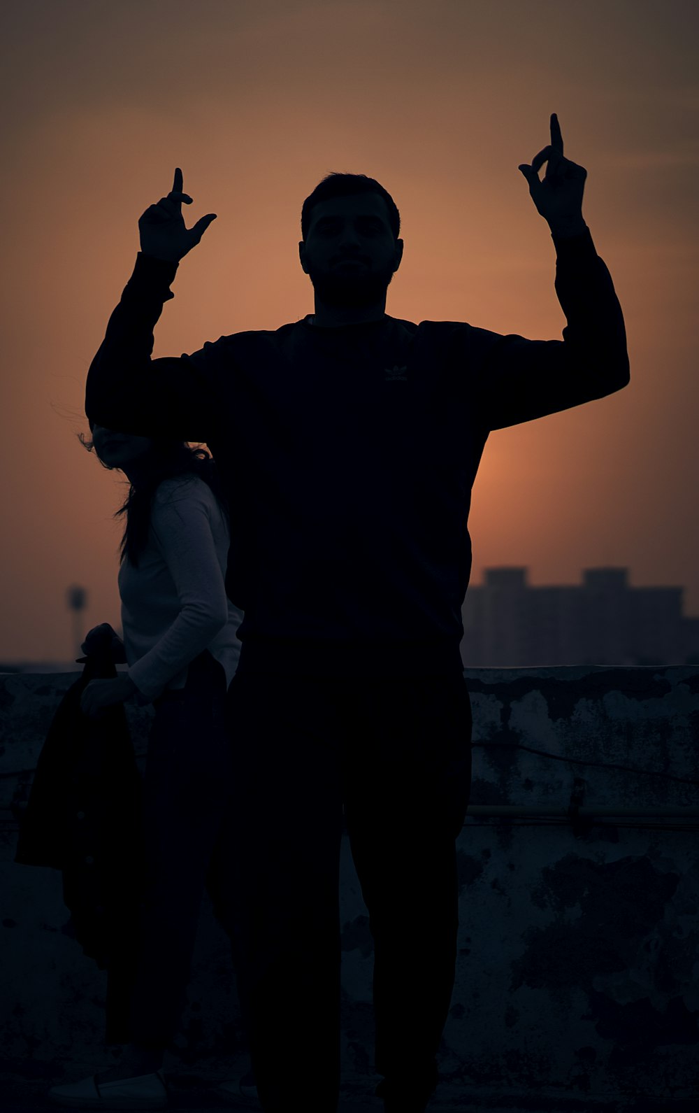 man in black crew neck t-shirt standing on gray concrete wall during daytime