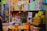 A cluttered store shelf displaying a variety of packaged products, mostly health and body care items. There's a prominent sign labeled 'SEX SPRAY' among the assortment of Tiger Balm products and other colorful boxes stacked neatly. The background is lined with more items, creating a busy and tightly packed retail environment.