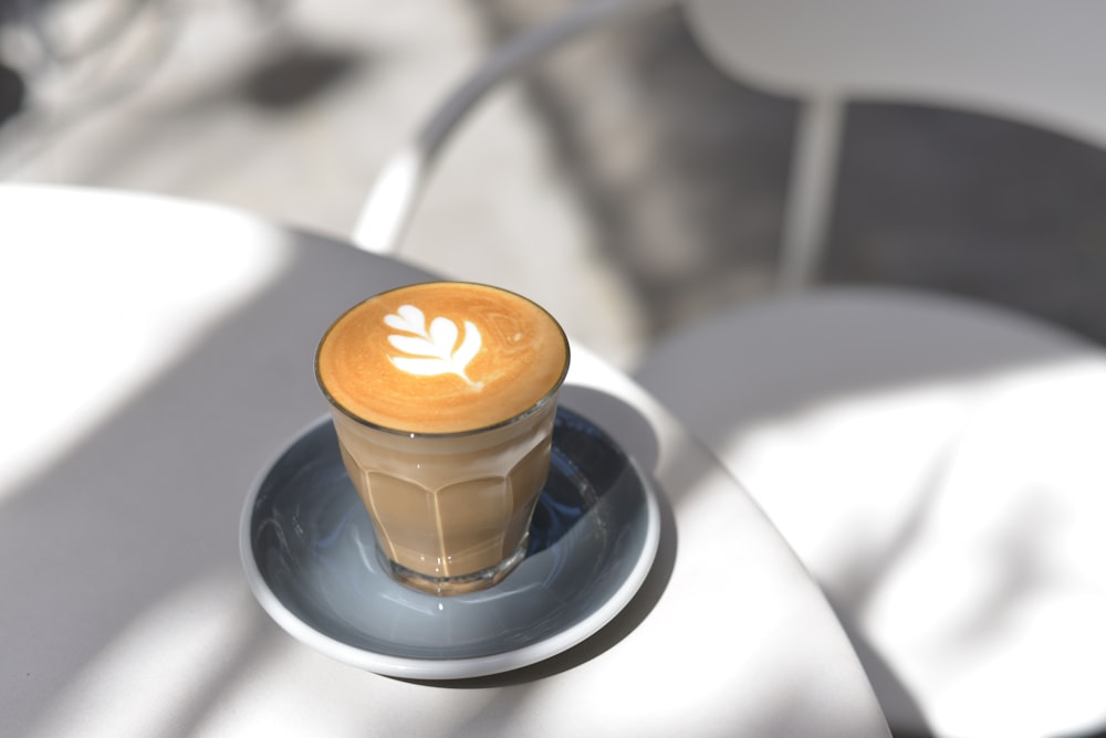 cappuccino in clear glass cup on saucer