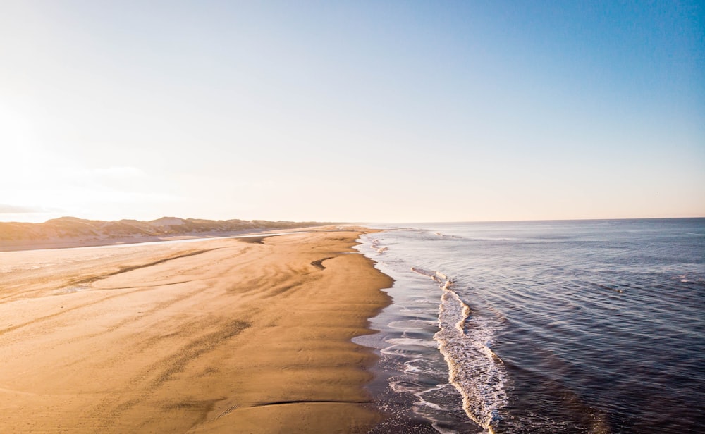 areia marrom perto do corpo de água durante o dia