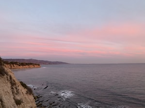 A serene coastal cliffside at sunset with waves gently crashing below, inviting peaceful exploration.