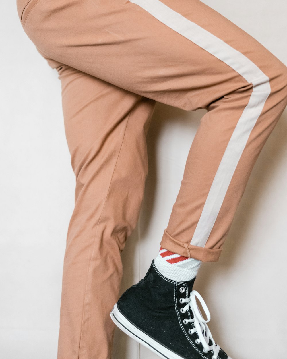 person in brown pants and black and white nike sneakers