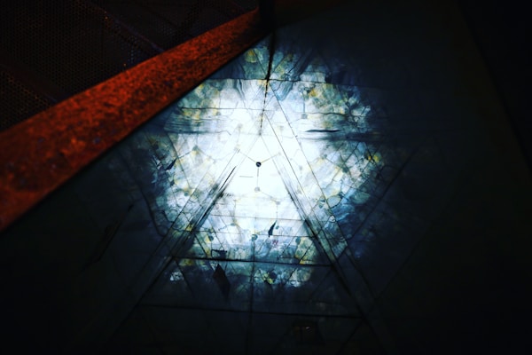 An artistic ceiling light piece with layered geometric shapes creating dynamic shadows in a boutique hotel lobby.