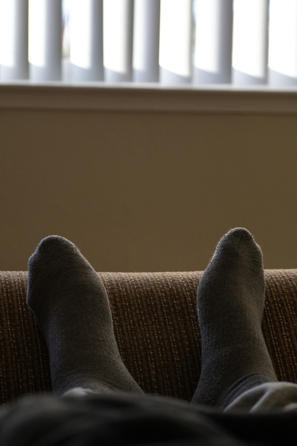 person in gray pants lying on brown textile