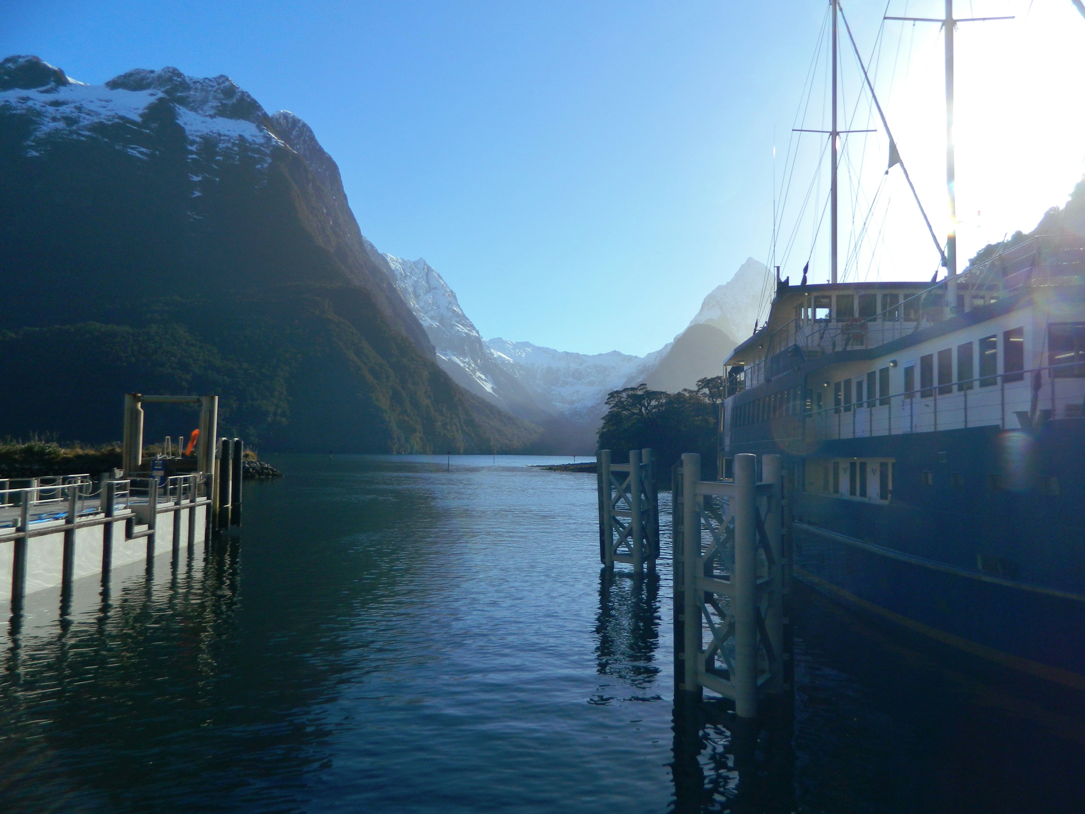 white and black boat on sea near mountain during daytime