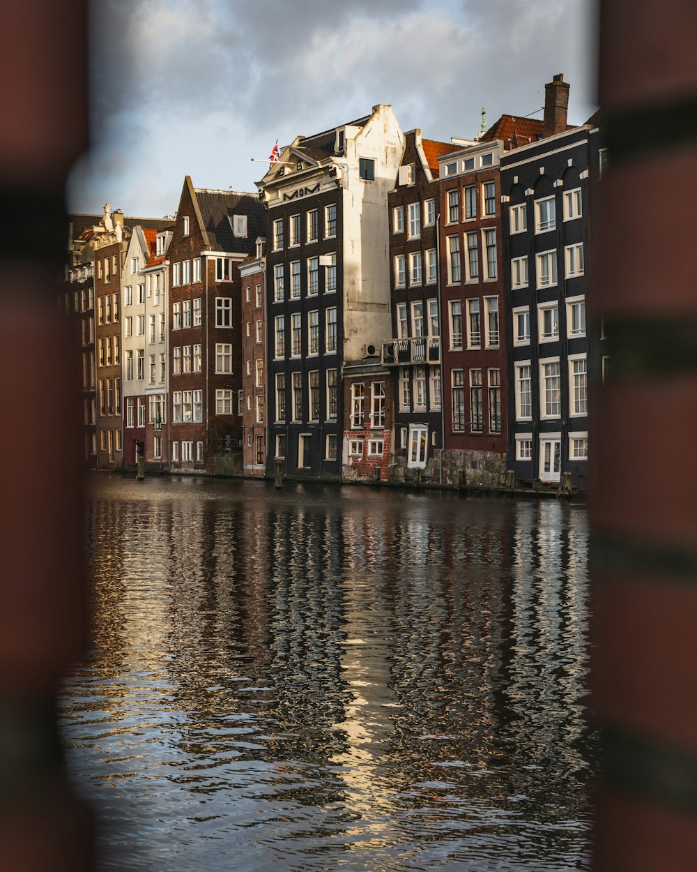 Bâtiment en béton brun et rouge à côté d’un plan d’eau pendant la journée