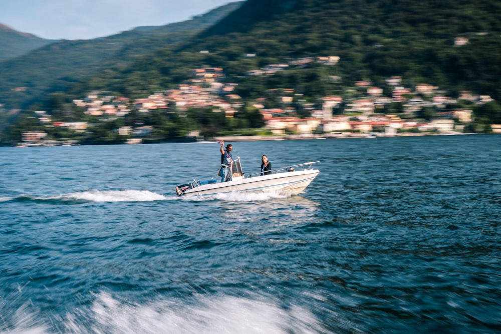 persone che cavalcano su una barca bianca e blu in mare durante il giorno