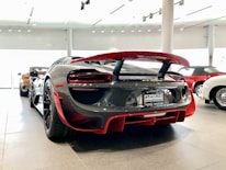 A sleek sports car parked beside a display case filled with collectible cards.