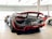 A sleek, high-performance sports car is prominently displayed indoors, highlighting its glossy finish and aerodynamic design. Surrounding it are other luxurious cars, suggesting a showroom setting.