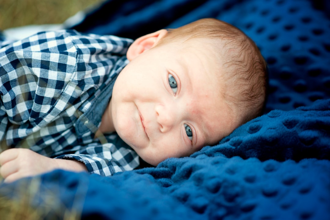 boy in blue white and black plaid shirt lying on blue textile
