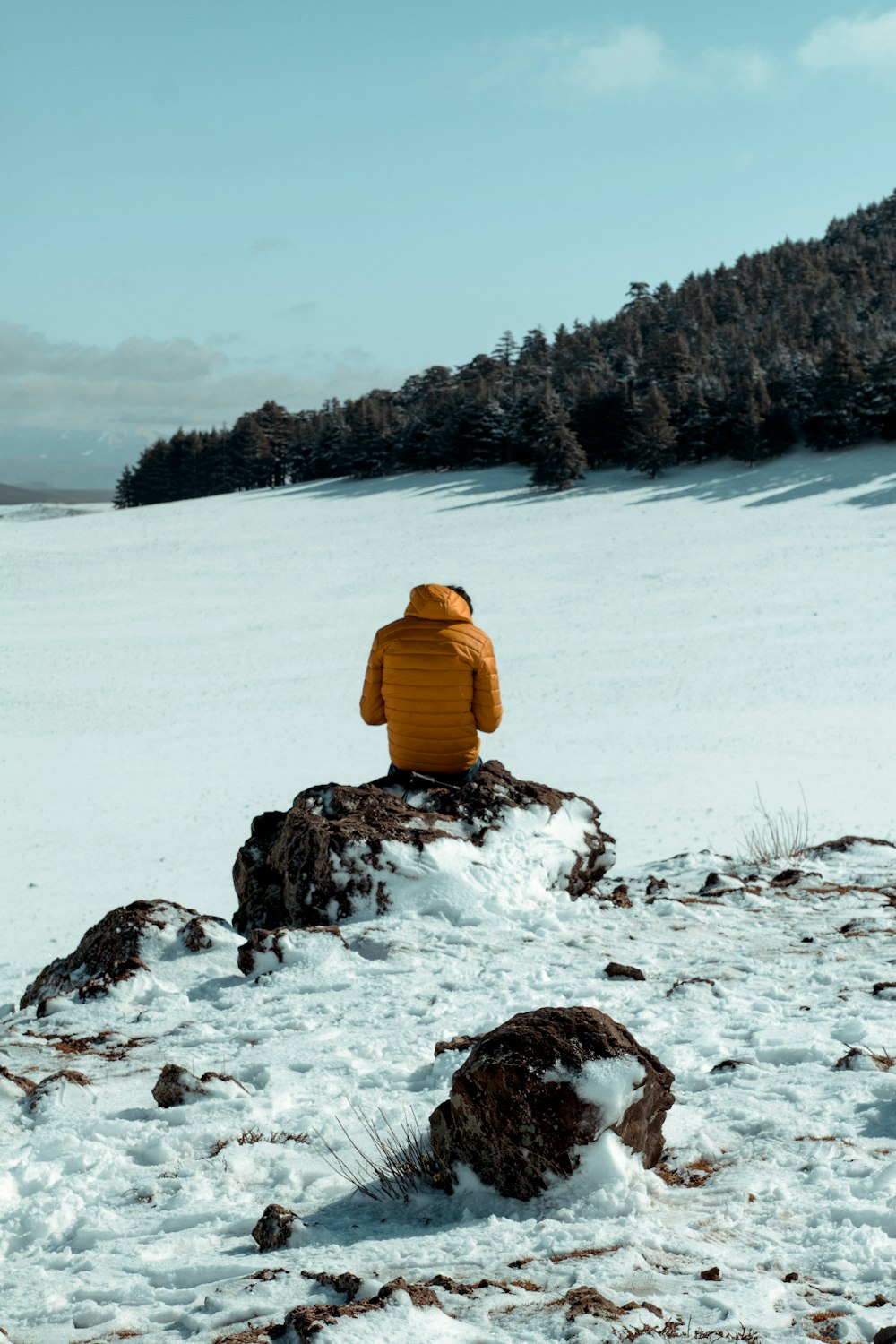 person in yellow jacket sitting on snow covered ground during daytime