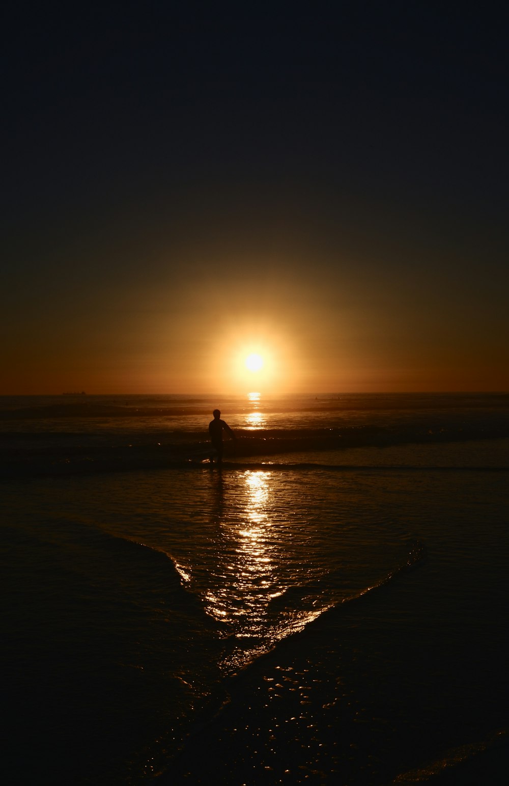 silhouette of person standing on beach during sunset