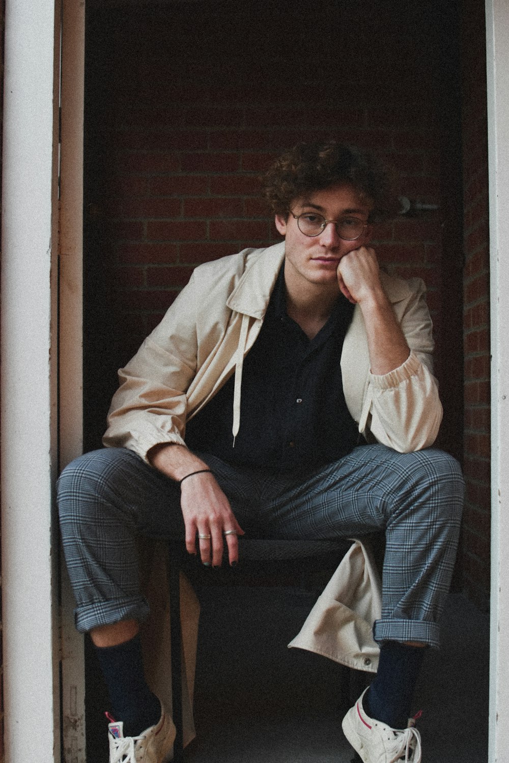 man in brown jacket and blue denim jeans sitting on brown wooden chair