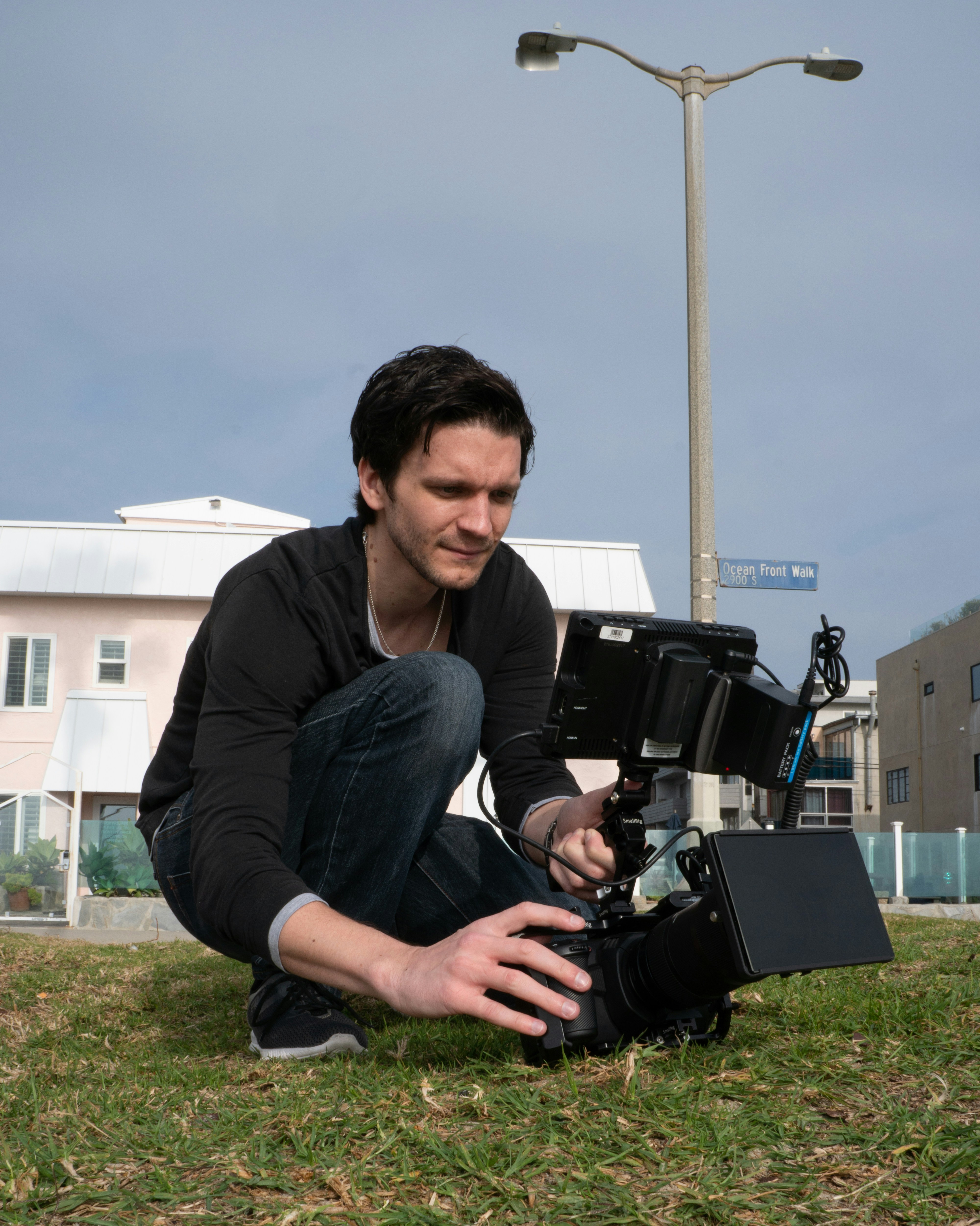 man in black jacket sitting on green grass field during daytime