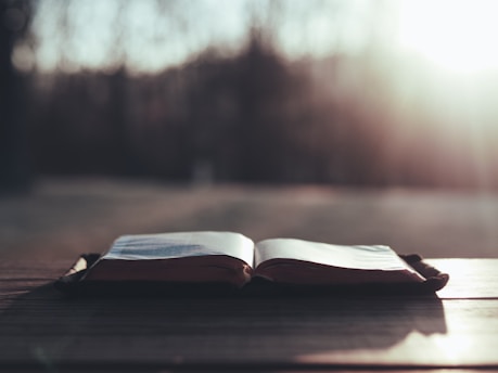 A serene sunrise illuminating an open book on a wooden table.