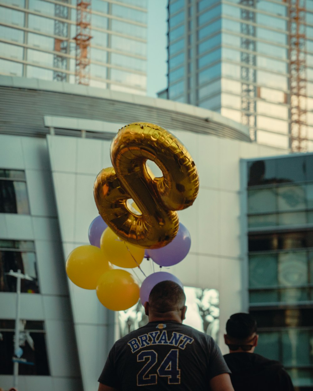 man in blue and white stripe shirt holding yellow balloons