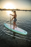 woman in blue and white shorts riding on white and green surfboard during daytime